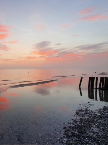 Strand bei Falshöft Sonnenaufgang über spiegelglattem Meer, Wellen rollen sanft an Kiesstrand
